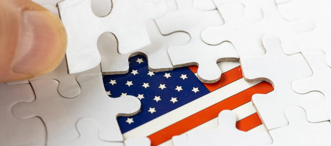en un rompecabezas de color blanco, una mano descubre la bandera de los EE.UU. bajo una de las piezas del puzzle