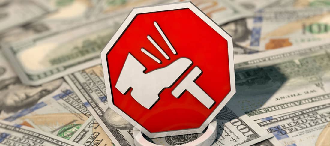 Señal simbólica con un pie pisando un freno, sobre billetes de dólar