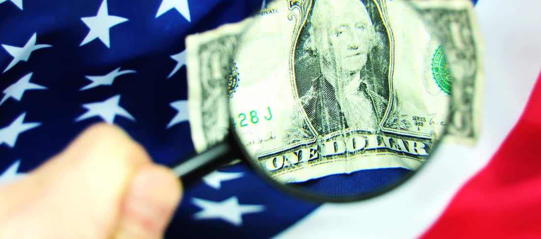 una lupa amplia la imagen de un dólar sobre una bandera de los EE.UU.