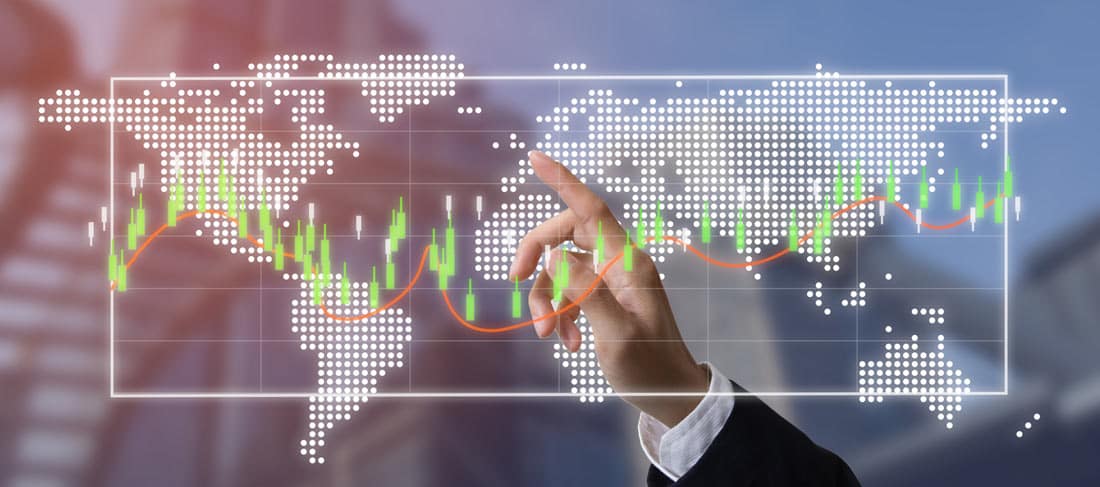 hombre de negocios señala los símbolos de gráfico de 'candlestick' superpuestos a un mapa del mundo esquemático y en el fondo de una ciudad fura de foco
