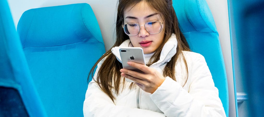 una joven observa la pantalla de su iphone mientras viaja sentada en un tren