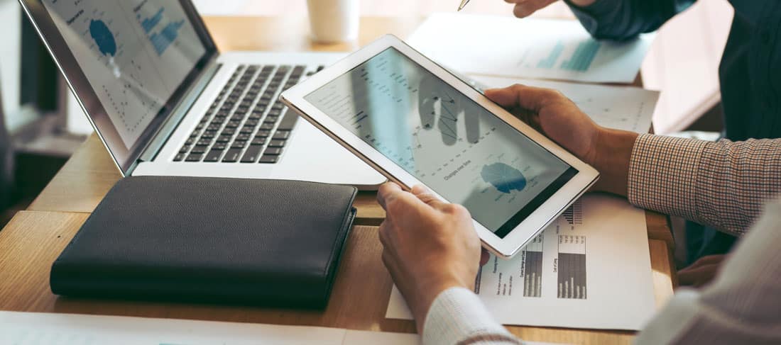 compañeros de trabajo conversan acerca de una gráfica de evolución vista en una tablet
